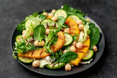 plate of avocado salad, chickpeas, pumpkins, cucumbers, poached eggs in plate on stone background