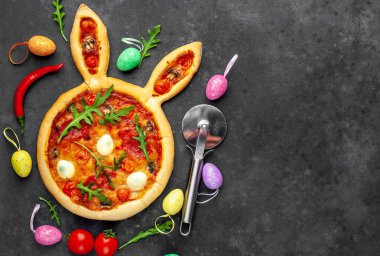 Yumurtalı tavşan şeklinde bayramlık Paskalya pizzası. Taş zeminde çok renkli Paskalya yumurtaları. Paskalya kutlaması kavramı.