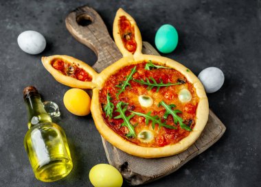 Yumurtalı tavşan şeklinde bayramlık Paskalya pizzası. Taş zeminde çok renkli Paskalya yumurtaları. Paskalya kutlaması kavramı.