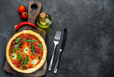 Lezzetli İtalyan pizzası, domates, peynir, bıldırcın yumurtası sosisi ve taş arka planda.