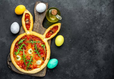 Yumurtalı tavşan şeklinde bayramlık Paskalya pizzası. Taş zeminde çok renkli Paskalya yumurtaları. Paskalya kutlaması kavramı.