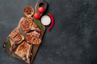 Baharatlı ızgara biftekler taştan bir arka planda kesim tahtasının üzerinde