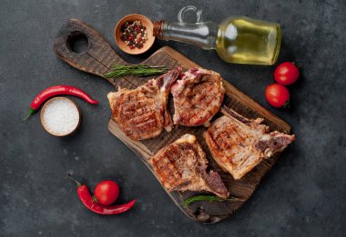 Baharatlı ızgara biftekler taştan bir arka planda kesim tahtasının üzerinde