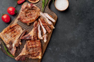 Baharatlı ızgara biftekler taştan bir arka planda kesim tahtasının üzerinde