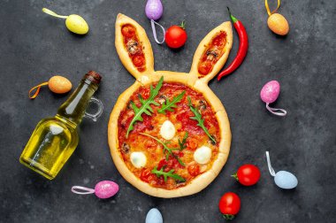 Yumurtalı tavşan şeklinde bayramlık Paskalya pizzası. Taş zeminde çok renkli Paskalya yumurtaları. Paskalya kutlaması kavramı.