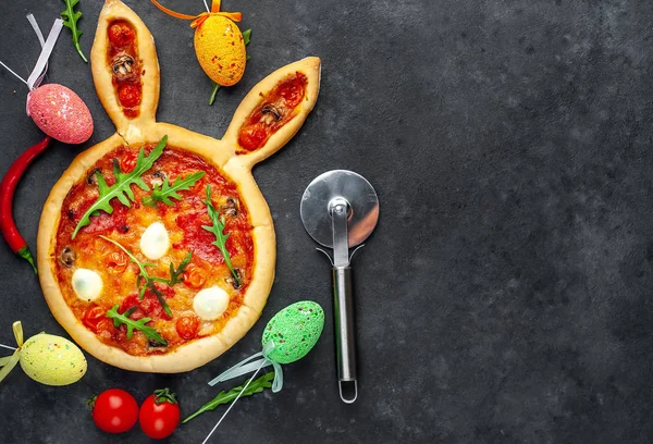 Yumurtalı tavşan şeklinde bayramlık Paskalya pizzası. Taş zeminde çok renkli Paskalya yumurtaları. Paskalya kutlaması kavramı.