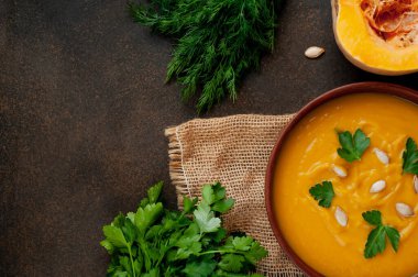 Koyu ahşap zemin üzerinde taze bitkiler ve baharatlarla kabak çorbası. Üst Manzara. Metin için boş alan