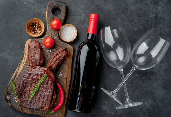 grilled steak with wine, rosemary and pepper on dark stone background.