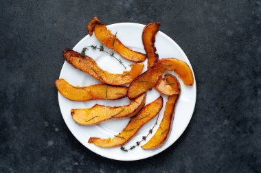 Baharatlı fırında balkabağı ve beyaz tabakta otlar