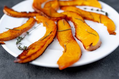 Baharatlı fırında balkabağı ve beyaz tabakta otlar