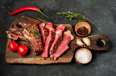 Kırsal masa arka planında ahşap tahtada taze ızgara et, otlar ve domatesler.