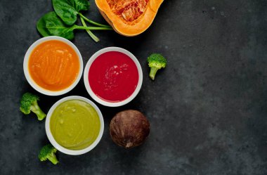 Kabak, havuç ve brokoli dolu kremalı kaseler kırsal masa arkasında.