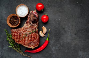 Terbiye edilmiş sebze ezmeli T-Bone bifteği ve domatesli köy masa arkaplanı.