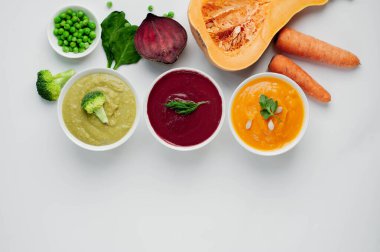 Lezzetli vejetaryen krema çorbaları kabak, havuç ve brokoli kaseleri kırsal masa arka planında.