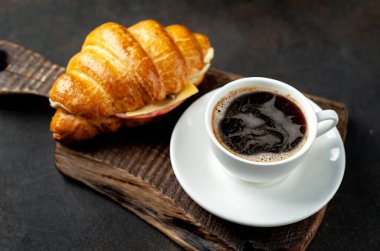 siyah sıcak espresso kahve fincanı ev yapımı kruvasan ile ahşap tahtada ahşap masa arkasında peynir ve jambon 