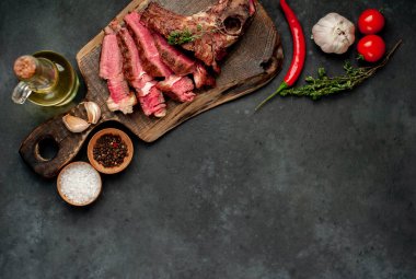 Kırsal masa arka planında ahşap tahtada taze ızgara et, otlar ve domatesler.