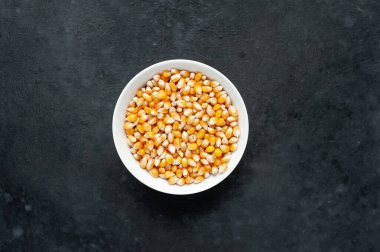 Kırsal masa arka planında beyaz kasede sarı çiğ mısır taneleri 