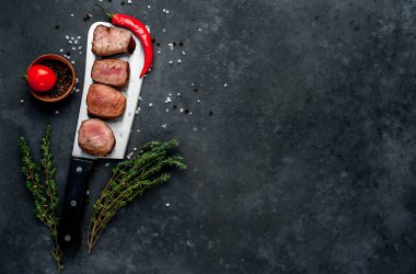 Bitkilerle ve biberiye dallarıyla dilimlenmiş madalyon bifteği.