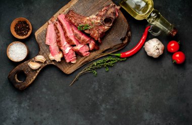 Kırsal masa arka planında ahşap tahtada taze ızgara et, otlar ve domatesler.