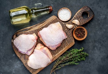 Çiğ tavuk butları ve arka planda baharatlar olan et bıçağı.