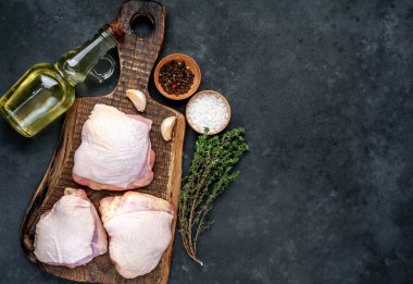 Çiğ tavuk butları ve arka planda baharatlar olan et bıçağı.