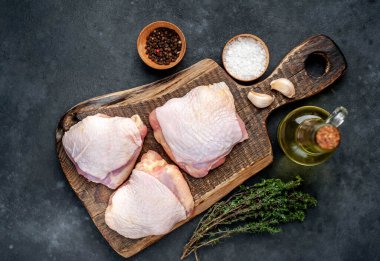 Çiğ tavuk butları ve arka planda baharatlar olan et bıçağı.