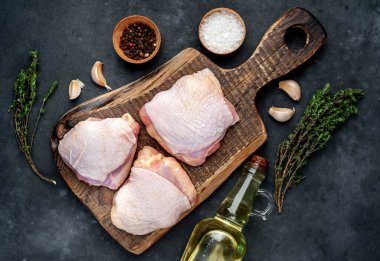 Çiğ tavuk butları ve arka planda baharatlar olan et bıçağı.