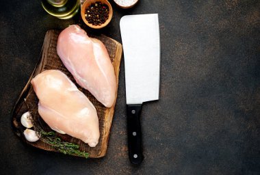 Bıçağın üstünde çiğ tavuk göğsü ve arka planda baharatlar var. Metnin için kopyalama alanı da var.