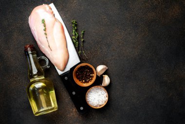 Bıçağın üstünde çiğ tavuk göğsü ve arka planda baharatlar var. Metnin için kopyalama alanı da var.