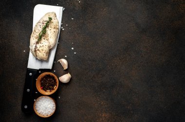 Bıçaklı tavuk göğsü. Arka planda baharatlar var. Metnin için kopyalama alanı var.