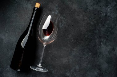 Bir şişe kırmızı şarap ve arka planda bir bardak şarap. Kopyalama alanı olan üst görünüm.