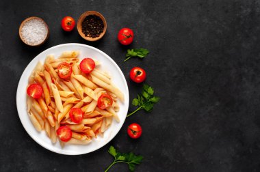 Domates soslu makarna ve arka planda beyaz bir tabakta ızgara tavuk budu.