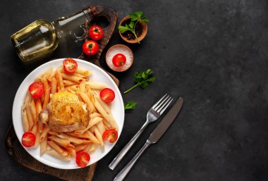 Domates soslu makarna ve arka planda beyaz bir tabakta ızgara tavuk budu.