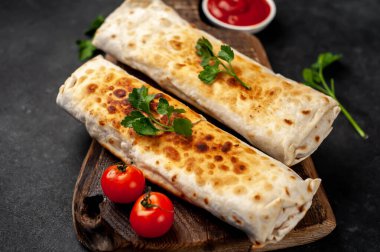 Burrito tavuk ve sebzeyle sarılmış, arka planda beton, Meksika shawarması var.