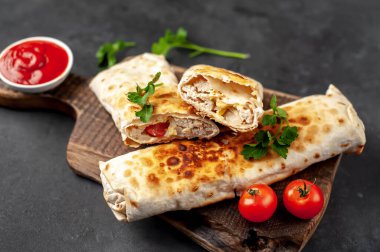 Burrito tavuk ve sebzeyle sarılmış, arka planda beton, Meksika shawarması var.