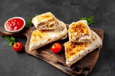 Burrito tavuk ve sebzeyle sarılmış, arka planda beton, Meksika shawarması var.