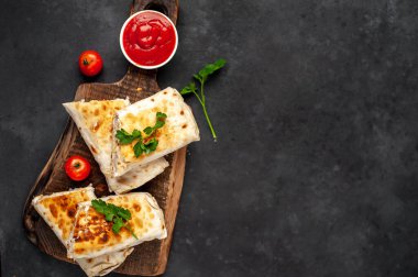 Burrito tavuk ve sebzeyle sarılmış, arka planda beton, Meksika shawarması var.