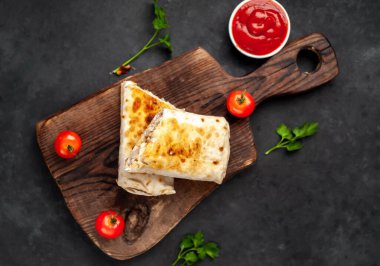 Burrito tavuk ve sebzeyle sarılmış, arka planda beton, Meksika shawarması var.