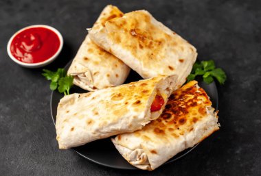 Burrito tavuk ve sebzeyle sarılmış, arka planda beton, Meksika shawarması var.