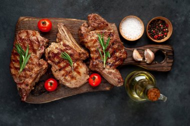 Koyu bir arka planda ızgara kaburga eti ve yağ şişesi.
