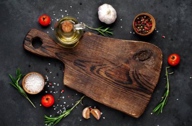 Ahşap tahta ve baharatlı malzemeler, biberiye ve domatesler koyu arka planda izole edilmiş, üst manzara