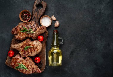 Koyu bir arka planda ızgara kaburga eti ve yağ şişesi.
