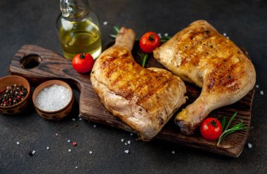 Tahta kesme tahtasında tavuk budu, biberiye ve kırmızı domates.