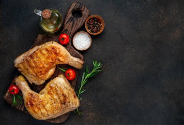 Tahta kesme tahtasında tavuk budu, biberiye ve kırmızı domates.