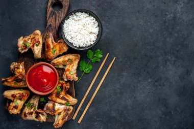 Kızarmış tavuk kanadı et ve kase pirinç ve kırmızı ketçap.