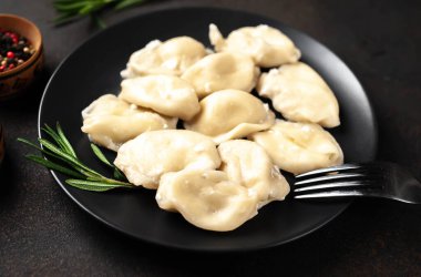 Koyu masa yüzeyinde pierogi köftesi ve çatal tabağı.