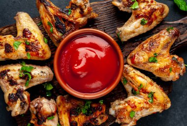 Yaklaş, ahşap tahta tavuk kanatlı et, koriander ve ketçap soslu kase.