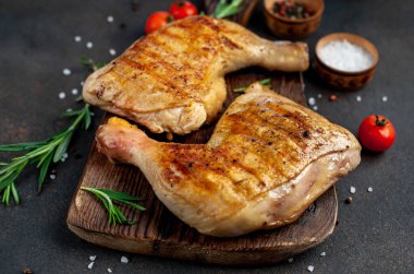 Tahta kesme tahtasında tavuk budu, biberiye ve kırmızı domates.