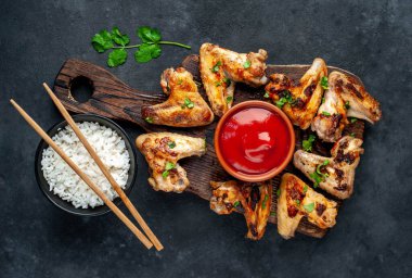 Kızarmış tavuk kanadı et ve kase pirinç ve kırmızı ketçap.