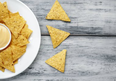 Tahta masa zemininde üçgen şekilli mısır tortilla cipsi ve sos, yakın görüş. 